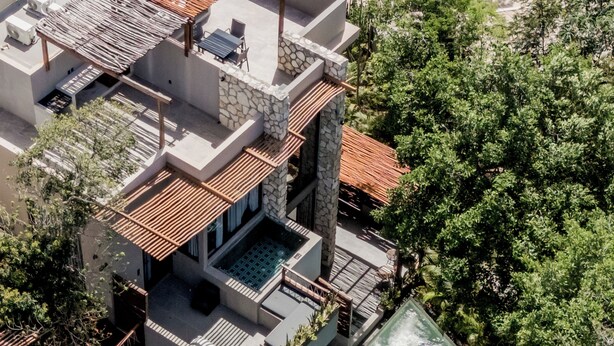 A modern multi-story building with a rooftop pool, outdoor seating, and a stone facade. - Siwa Tulum 2BR Luxury Condo with Private Pool + Rooftop (Tulum)
