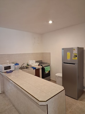 A kitchen with a microwave, stove, sink, and refrigerator.