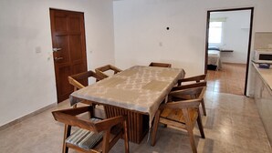 A spacious dining area with a large table and wooden chairs, a ceiling fan, and a door leading to another room. - Cozy house 150 meters from the Beach in Chicxulub Puerto (Chicxulub)