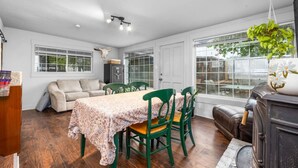 Quarto com mesa de jantar, cadeiras, sofá, lareira e janelas amplas.