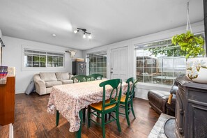 Una habitación con una mesa de comedor, sillas, un sofá, una chimenea y ventanas amplias.