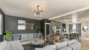 A modern living room with a grey sofa set, a coffee table, and a TV mounted on the wall.