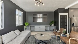 A modern living room with a grey sofa, a round coffee table, and a grey cabinet with a flat-screen TV.