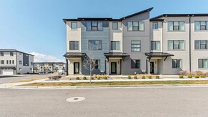 A multi-story residential building with a flat roof, large windows, and a landscaped front yard.