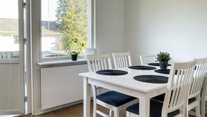 A dining area with a white table and chairs, black placemats, and potted plants. - 6 Person Holiday Home in Timmernabben (Fliseryd)