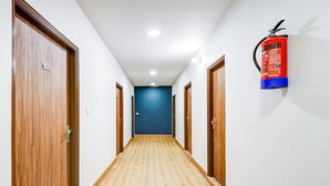 Een hal met houten deuren, een blauwe wand aan het einde en een brandblusser aan de muur.