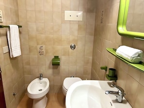 A bathroom with a bidet, toilet, sink, towel rack, and a green shelf with a towel. - Studio Just 50 mt From the Beach (Lignano Sabbiadoro)