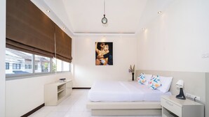 Un dormitorio con cama, mesita de noche, ventana con persianas y un cuadro en la pared.