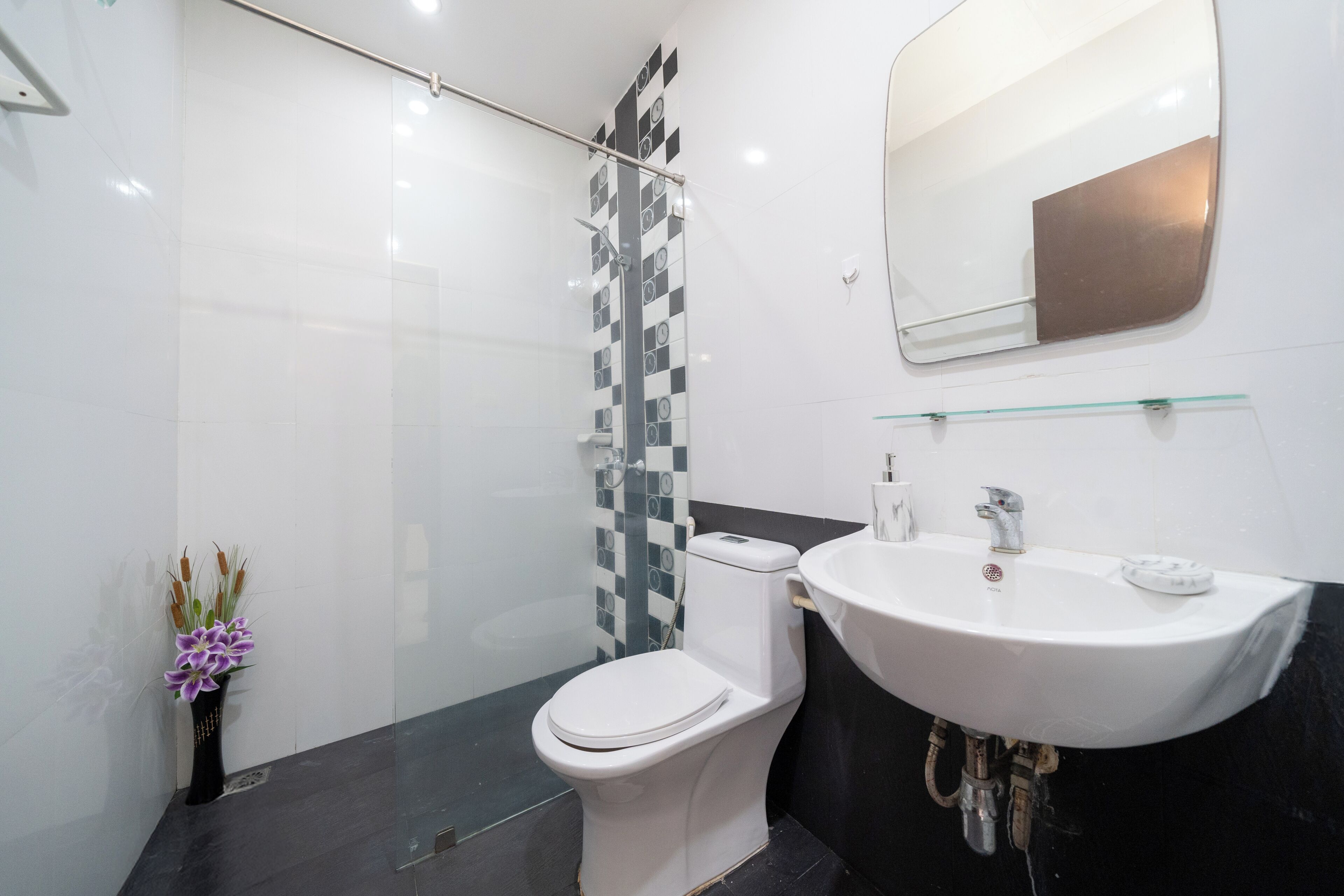 A modern bathroom with a toilet, shower, sink, and a mirror.