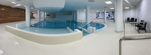 A swimming pool area with a curved design, multiple seating areas, and a mural on the wall. - 150m from ski slopes, 1st floor, view ski slopes, swimming pool, balcony, tv, ski locker, 29m² (Eaux-Bonnes)