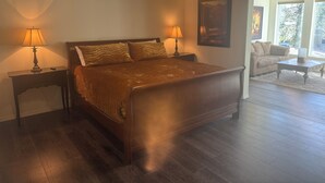 A bedroom with a large bed, two bedside lamps, a nightstand, a window, and a view of the outdoors. - WATERFRONT PARADISE (Spokane)