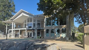 A two-story house with a balcony, a covered porch, and a driveway leading to the entrance. - WATERFRONT PARADISE (Spokane)