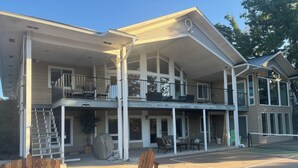 A two-story house with a covered porch, outdoor seating, and a basketball court. - WATERFRONT PARADISE (Spokane)