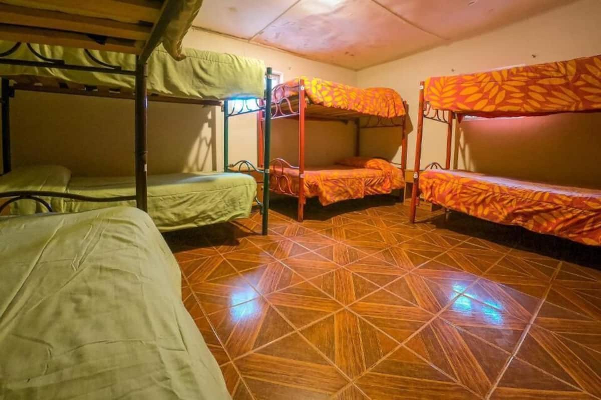 A dormitory room with bunk beds, a tiled floor, and a simple layout.