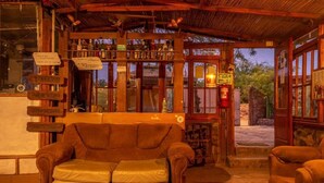 A rustic bar area with wooden furniture, a leather couch, and various bottles. - La Casa del Sol Naciente (San Pedro de Atacama)