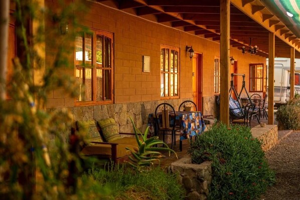 A covered outdoor seating area with stone walls, wooden beams, and a table with chairs. - La Casa del Sol Naciente (San Pedro de Atacama)