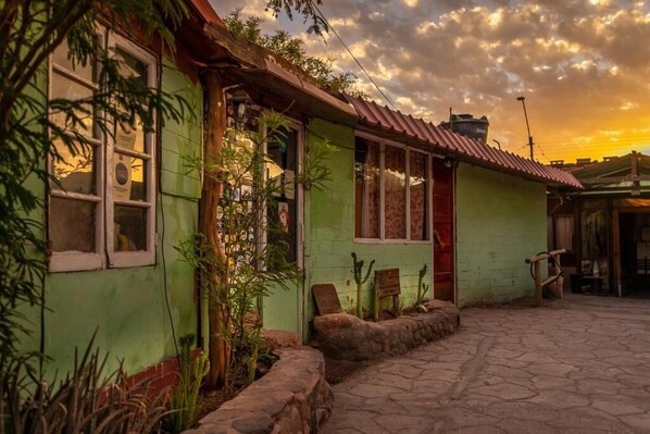 Un edificio verde con techo rojo, sendero de piedra y plantas.