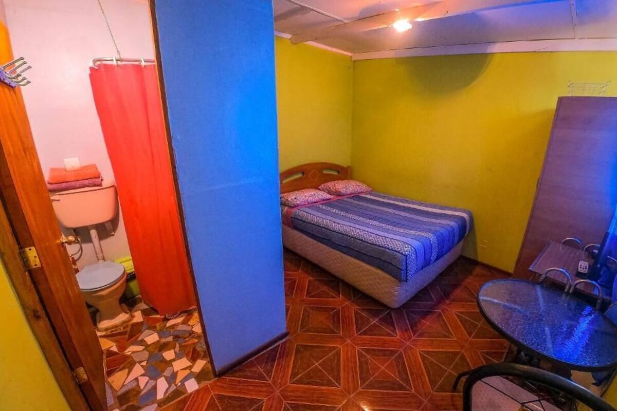 A small room with a bed, a table, and a toilet.