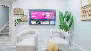 Una sala de estar moderna con un televisor de pantalla plana, dos sillones, una mesa de centro y una escalera.