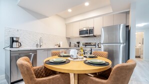 Una cocina moderna con una mesa de comedor para cuatro personas, electrodomésticos de acero inoxidable y una distribución compacta.