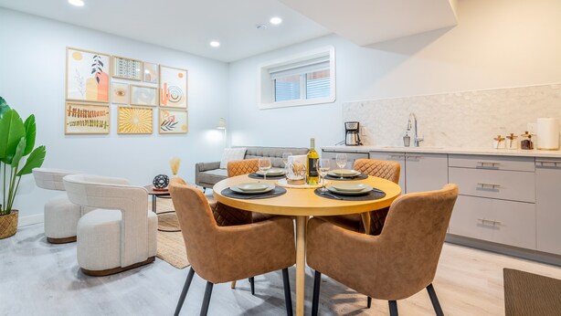 Un comedor con una mesa redonda, seis sillas y una cocina al fondo.