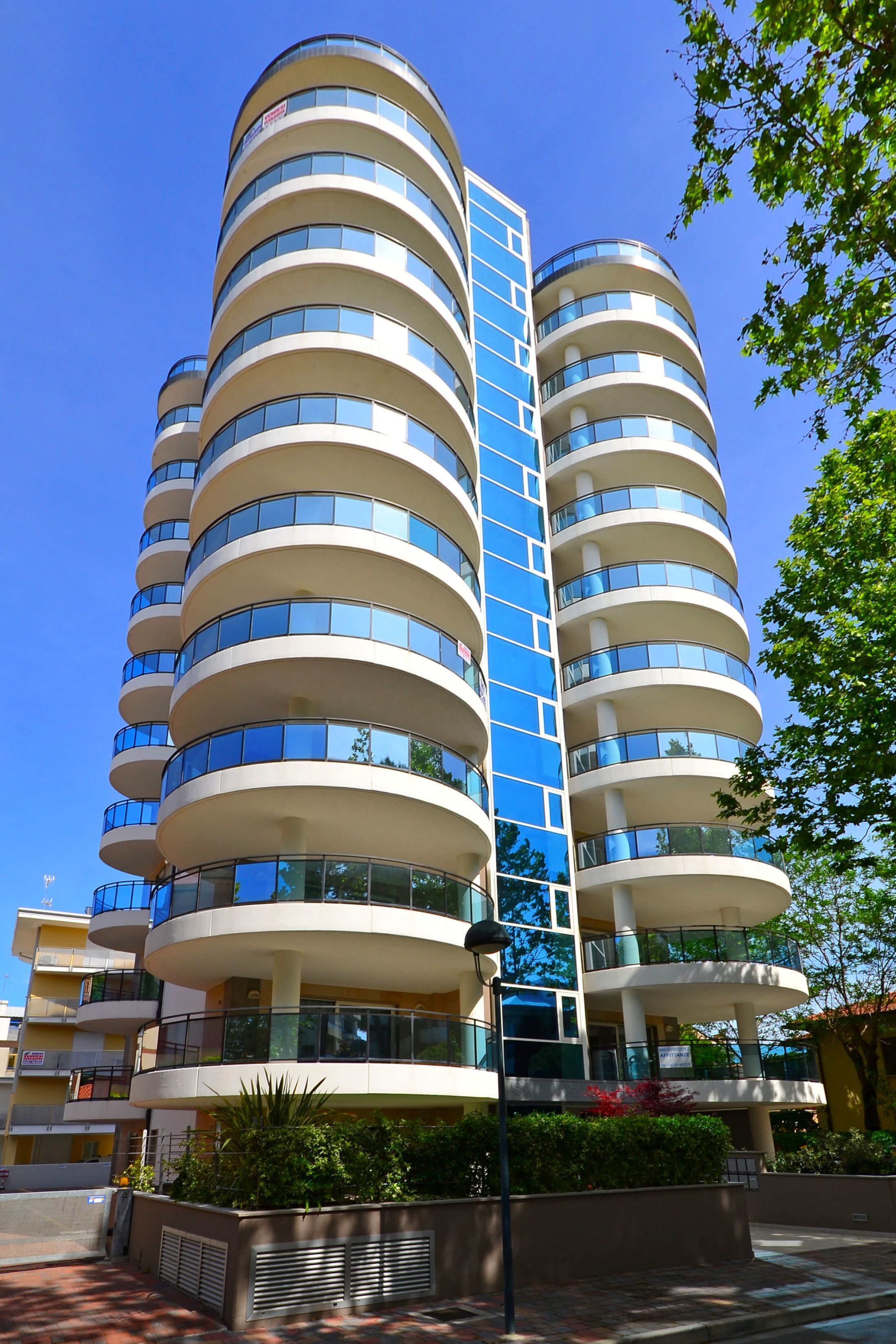 Un edificio de varios pisos con un diseño arquitectónico moderno, con balcones y ventanas grandes.