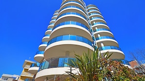 Ein mehrstöckiges Hotel mit einer geschwungenen Fassade, Balkonen und großen Fenstern.