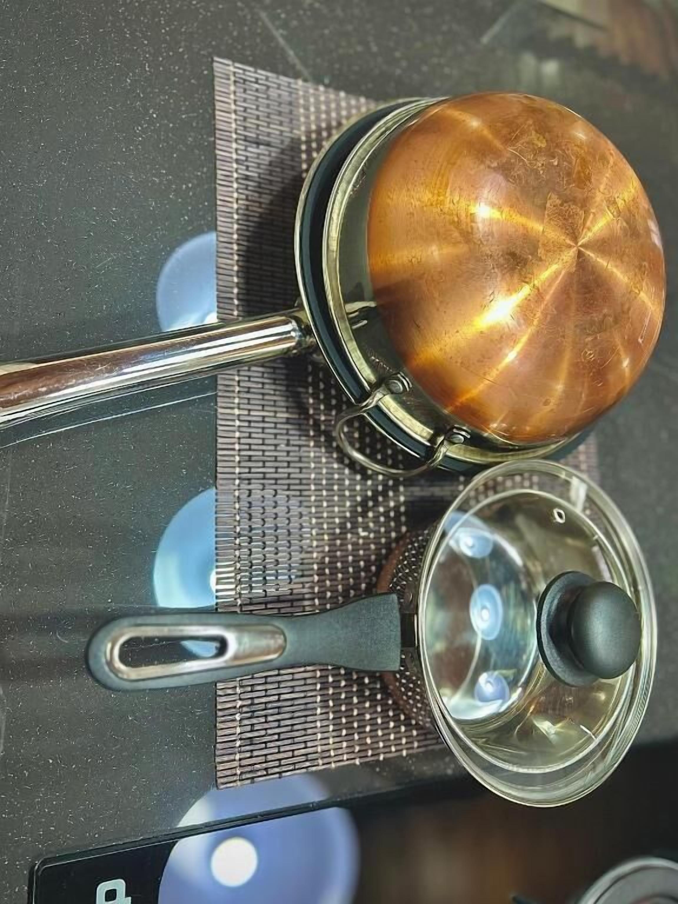 Een koffiezetapparaat met glazen kan, een metalen lepel en een deksel op een tafel.