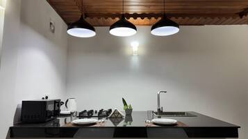 A modern kitchen with a black countertop, white chairs, a stove, and pendant lights.