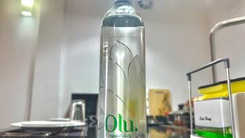 Eine Flasche Oulu-Tropic-Wasser steht auf einem Tisch in einem Raum mit weißer Wand und Deckenlampe.