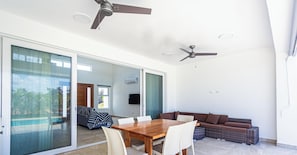 Ein moderner Wohnbereich mit Esstisch, einer Couch und Deckenventilatoren.