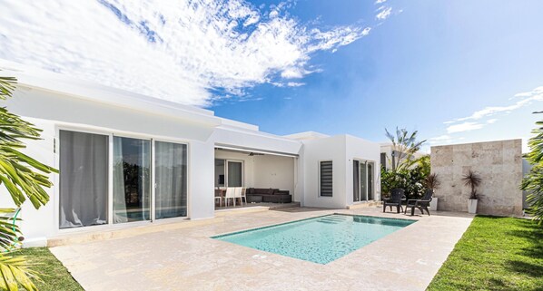 Ein modernes Haus mit Swimmingpool, großen Schiebeglastüren und einer Terrassenfläche.