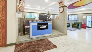 A reception desk labeled 'TOWNHOUSE' with a computer, a statue, and a clock on the wall. - Townhouse Vellore Fort (Vellore)