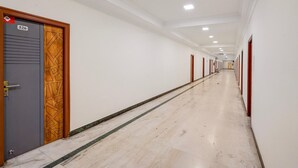 A long, narrow hallway with a marble floor, white walls, and doors on both sides. - Townhouse Vellore Fort (Vellore)