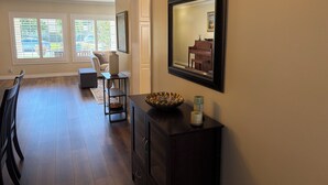 A spacious living room with a dining area, large windows, a piano, and a dark wooden cabinet. - Clean, Bright & Comfortable Pool Home w/separate Poolhouse Studio (Los Angeles)