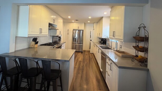 A modern kitchen with white cabinets, stainless steel appliances, and a central island with bar stools. - Clean, Bright & Comfortable Pool Home w/separate Poolhouse Studio (Los Angeles)