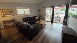 A spacious living area with a black leather sofa, a wooden coffee table, and a ceiling fan. - Clean, Bright & Comfortable Pool Home w/separate Poolhouse Studio (Los Angeles)