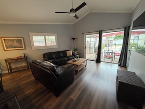 A spacious living area with a black leather sofa, a wooden coffee table, and a ceiling fan. - Clean, Bright & Comfortable Pool Home w/separate Poolhouse Studio (Los Angeles)