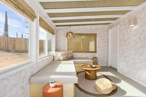 A room with a large window, a sofa, a small round table, and a decorative lamp. - Zen House, serene & close to everything (Yucca Valley)