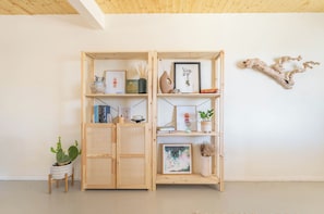 A wooden bookshelf with various items including books, framed pictures, and decorative objects. - Zen House, serene & close to everything (Yucca Valley)