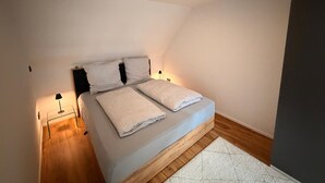 Quarto com uma cama, duas mesas de cabeceira e uma luminária na parede.