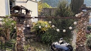 Um pátio com churrasqueira, pilares de pedra e um banco de madeira.