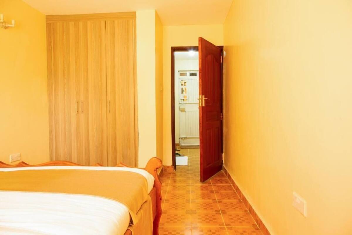 A bedroom with a bed, a wardrobe, and a bathroom visible through an open door.