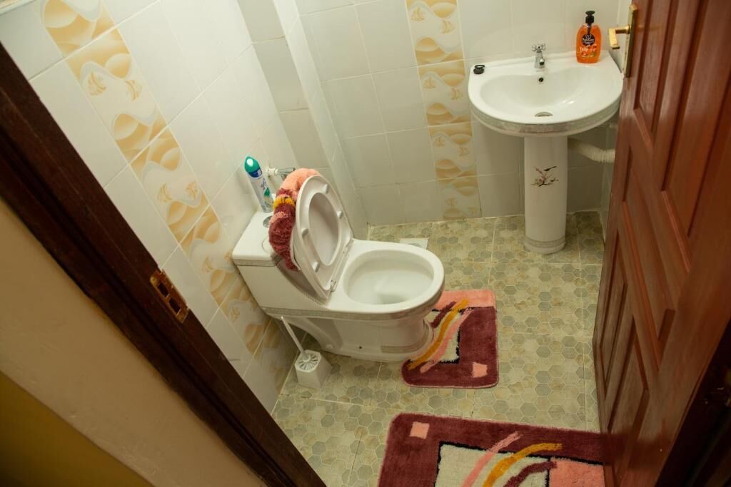 Un baño con inodoro, lavamanos y piso estampado.