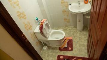 Un baño con inodoro, lavamanos y piso estampado.