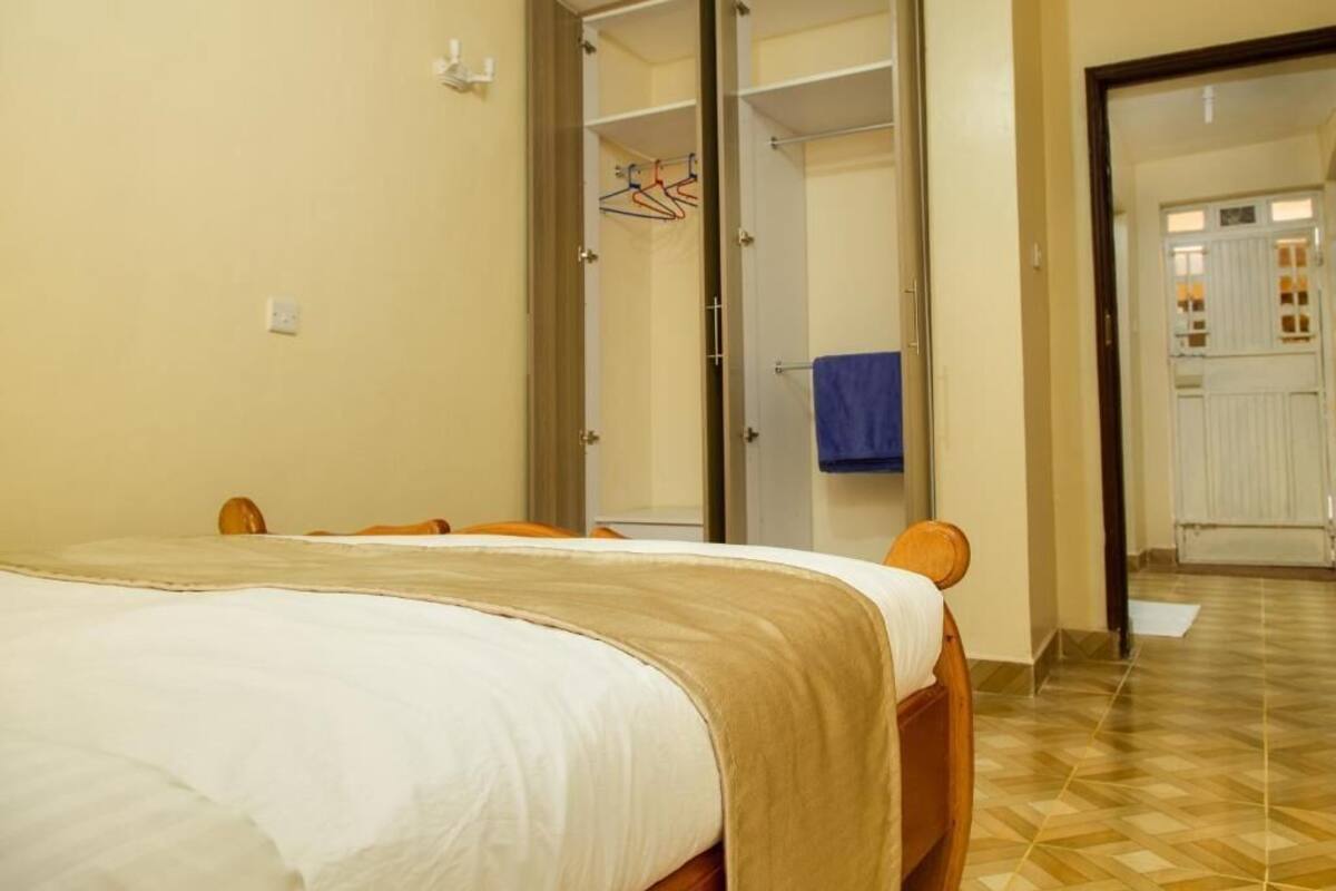A bedroom with a bed, a wardrobe, and a bathroom visible through an open door.