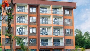 A multi-story building with a symmetrical facade, multiple balconies, and a central entrance. - Ashville Homes (Meru)