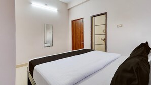 A hotel room with a bed, a wooden door, a mirror, and a light fixture. - Classic Chhathrapathi Residency (Tirupati)