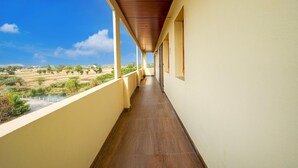 A corridor with a view of a landscape, a covered balcony, and a building with a light-colored exterior. - Classic Chhathrapathi Residency (Tirupati)