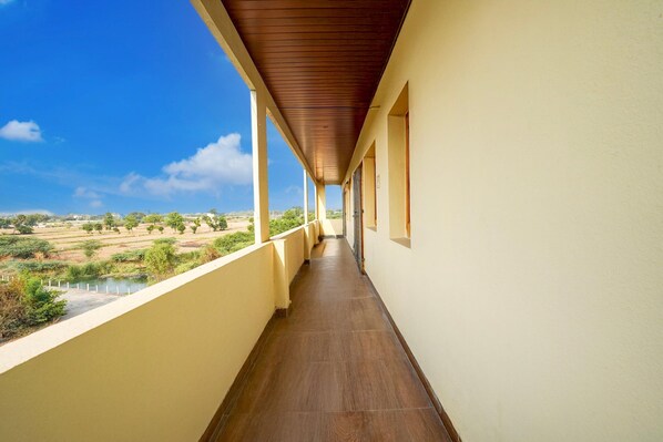 Ein Korridor mit Blick auf eine Landschaft, ein überdachter Balkon und ein Gebäude mit heller Fassade.